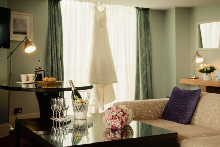 Osprey Hotel Weddings Bridal Suite with wedding dress hanging, champagne on ice and floweral bouquet